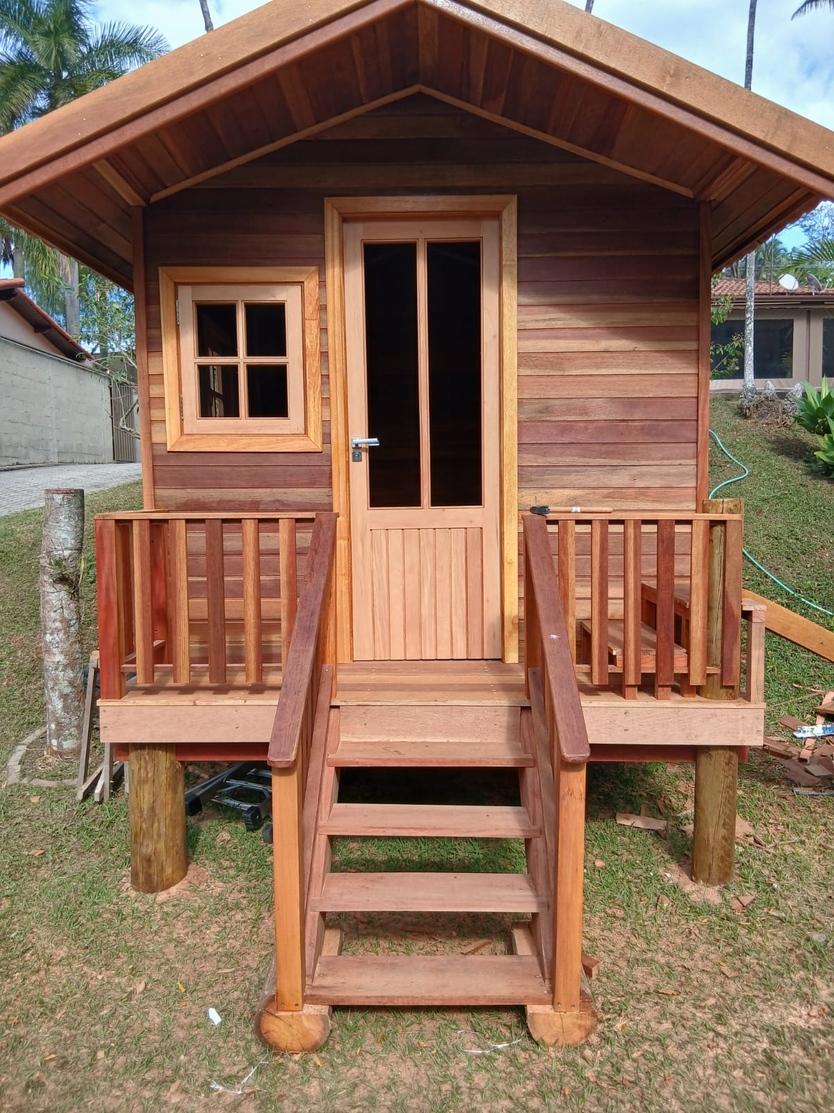 Fachada de casinha de madeira com porta, janela e escada